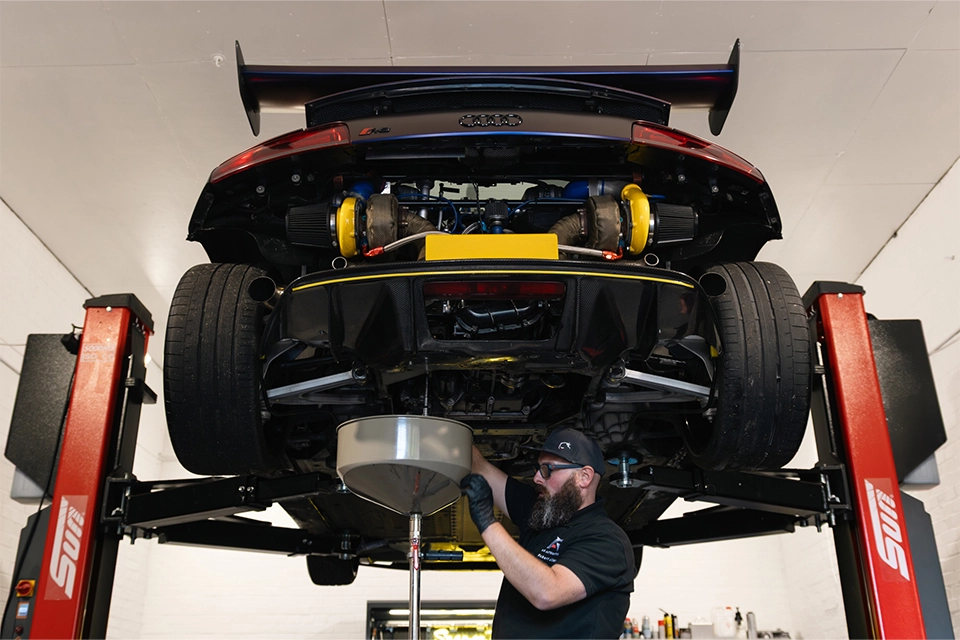 Mechanic draining oil from a Audi raised on a car lift
