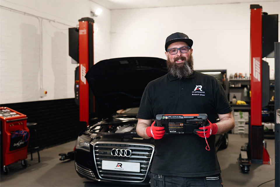 Mechanic holding a diagnoses iPad standing in front of Audi