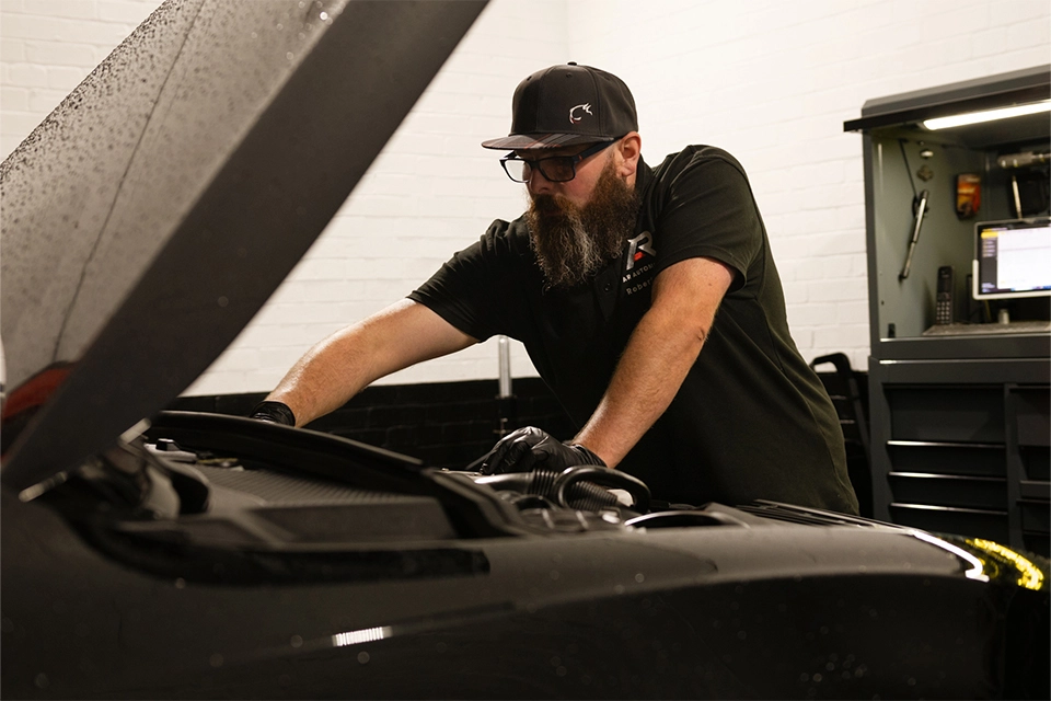 Mechanic works under the hood of vehicle